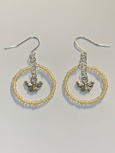 Load image into Gallery viewer, Silver coloured findings with a circle of yellow mini beads, framing a little bee charm in the centre. Earrings lay flat against a white background
