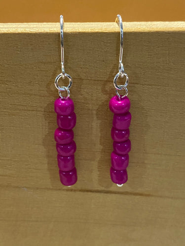Handmade beaded drop earrings. Silver coloured findings and a single strand of beads in a solid bright pink. 