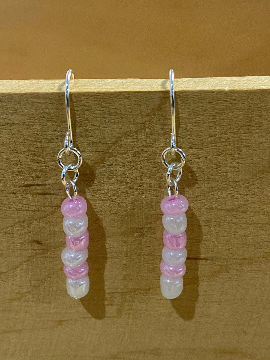 Beaded drop earrings with pearly white and light pink alternate beads, in a single strand with silver coloured earring hooks and and findings
