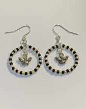 Load image into Gallery viewer, Silver coloured findings with a circle of alternate black and yellow mini beads, framing a little bee charm in the centre. Earrings lay flat against a white background
