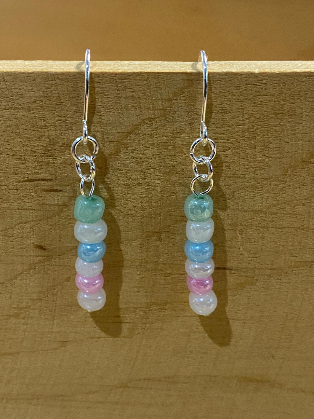 Handmade beaded drop earrings with pastel green, blue and pink beads alternated with pearly white beads in a single strand. Silver coloured earring hooks and findings.