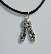 Load image into Gallery viewer, silver coloured ballet slippers charm on a black cord necklace. image shows the back of the charm which includes the soles of the ballet shoes. All lay flat against a white background
