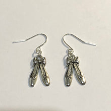 Load image into Gallery viewer, Silver coloured earrings with ballet slipper charms, laying flayt against a white background
